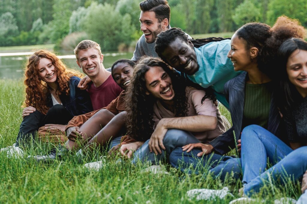 Multiethnic happy group of people having fun outdoor by the lake - Focus on blond man face